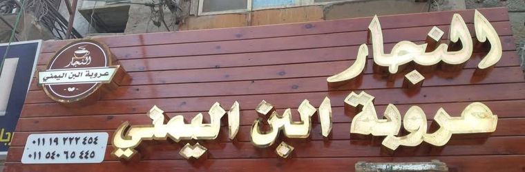 حروف بارزة ذهبية على خلفية خشبية لمحل النجار عروبة البن اليمني